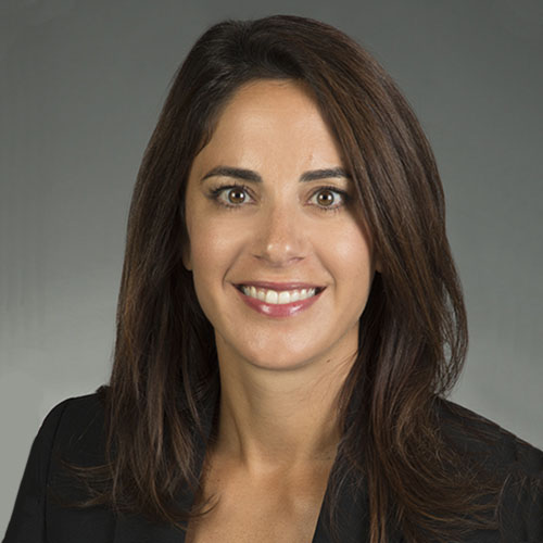 Head shot of a woman with straight brown hair in front of a gray background