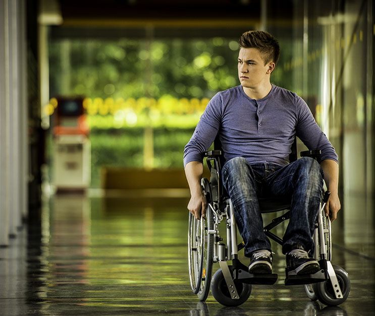 Young man in wheelchair traveling down hallway