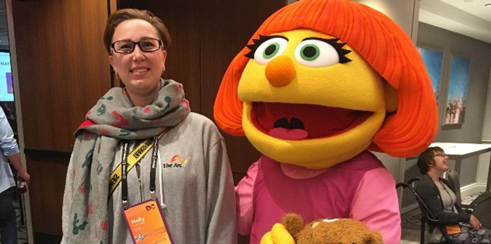Convention attendee stands and poses with Muppet from Sesame Street